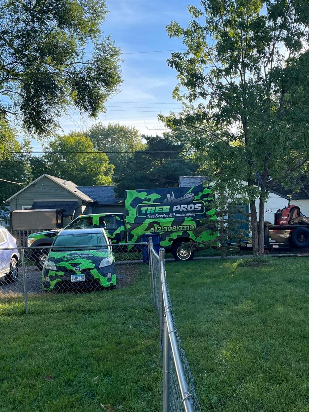 Green and black Tree Pros truck parked near a house in a residential area.
